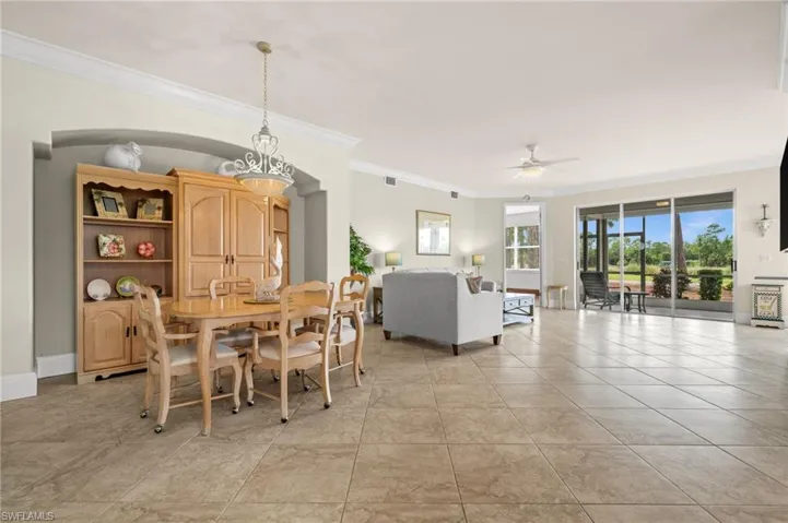 Dining space featuring ornamental molding, a chandelier, light tile patterned flooring, and ceiling fan