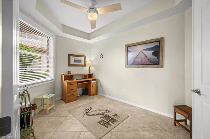 Office space with a ceiling fan, a tray ceiling, and light tile patterned floors