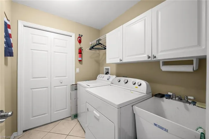 Laundry area featuring light tile patterned flooring, cabinet space, and washer and dryer