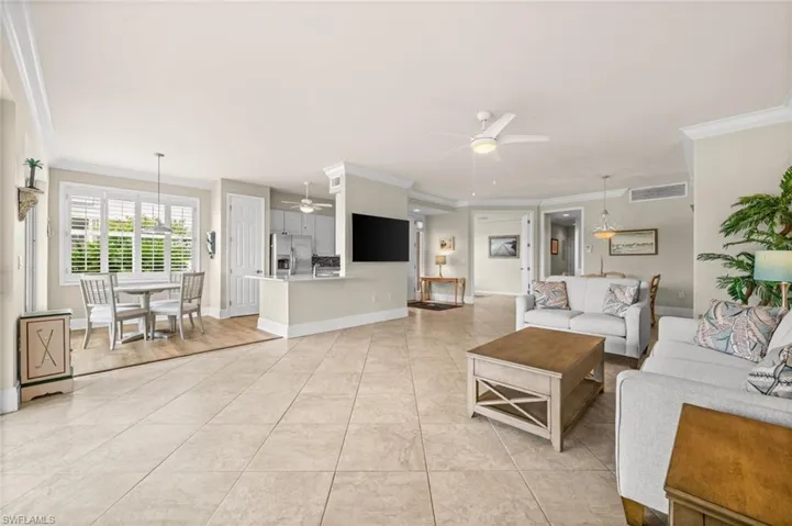 Living area with crown molding, light tile patterned flooring, and a ceiling fan