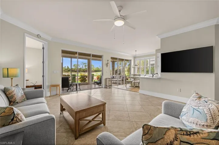 Tiled living area with ornamental molding and ceiling fan