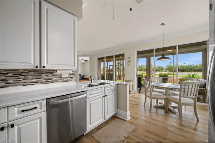 Kitchen featuring a ceiling fan, white cabinetry, stainless steel appliances, ornamental molding, and light wood-style flooring