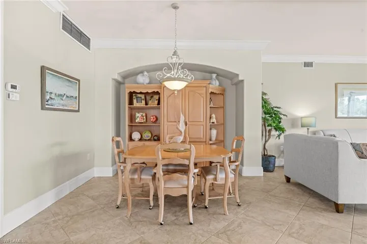 Dining room featuring ornamental molding, light tile patterned floors, and arched walkways