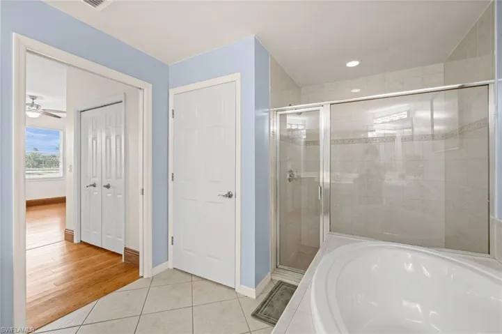 Bathroom featuring light tile patterned flooring, a stall shower, a bath, and recessed lighting