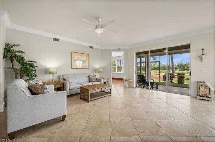 Living room with crown molding, light tile patterned floors, and a ceiling fan