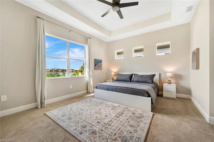 Bedroom featuring a raised ceiling, ceiling fan, and carpet floors
