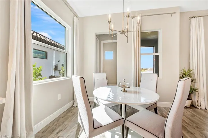 Dining room with a healthy amount of sunlight, light hardwood / wood-style floors, and an inviting chandelier