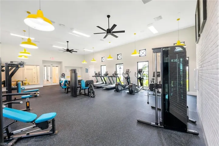 Exercise room featuring ceiling fan and a towering ceiling