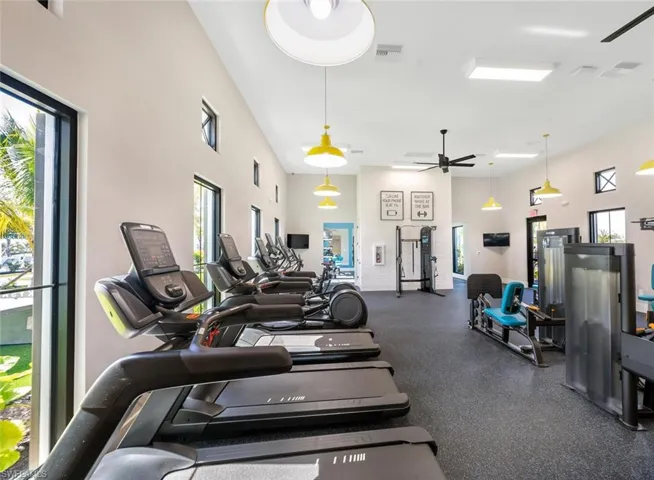 Exercise room with a high ceiling, ceiling fan, and a wealth of natural light