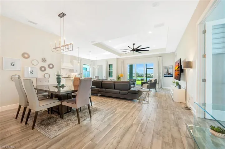 Dining area with a tray ceiling, ceiling fan with notable chandelier, and light hardwood / wood-style flooring