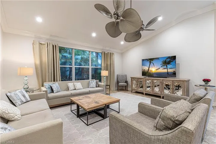 Living room featuring vaulted ceiling, ceiling fan, and crown molding
