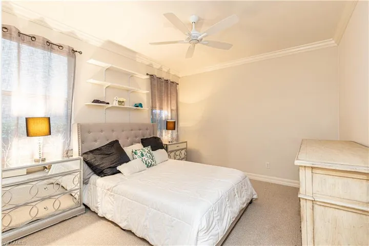 Carpeted bedroom with ceiling fan and ornamental molding