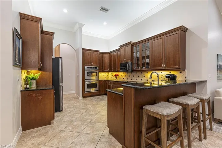 Kitchen with kitchen peninsula, light tile patterned floors, stainless steel appliances, and tasteful backsplash