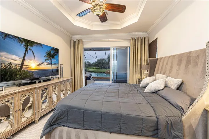 Bedroom with a raised ceiling, ornamental molding, ceiling fan, and access to exterior