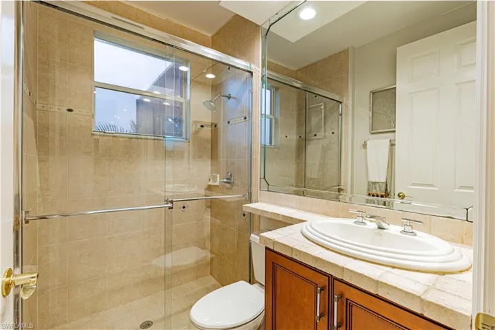 Bathroom featuring walk in shower, vanity, and toilet