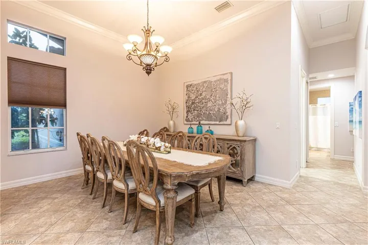 Tiled dining space featuring a chandelier and ornamental molding