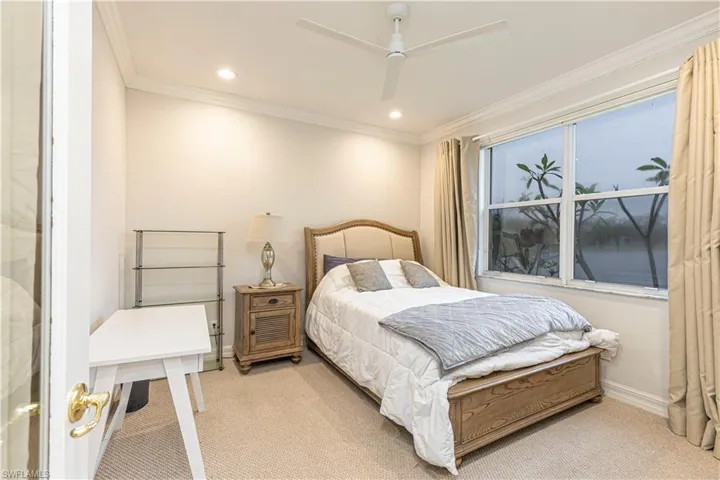 Bedroom with light carpet, ceiling fan, and crown molding