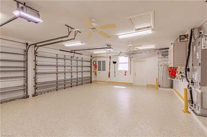 Garage with a garage door opener, electric panel, and ceiling fan