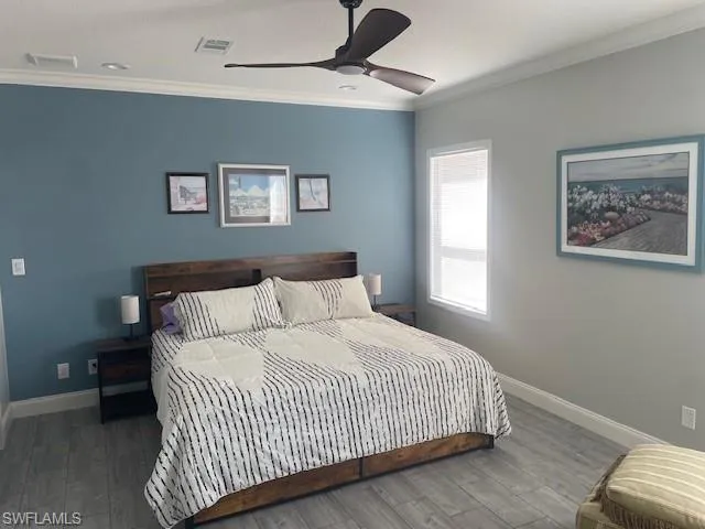 Bedroom featuring ornamental molding, wood finished floors, and a ceiling fan