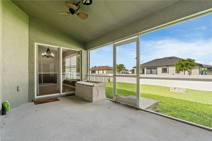 Concrete patio with screened enclosure, ceiling fan, and sliding glass door access to the interior