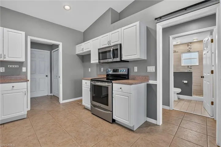 Kitchen space featuring white cabinetry, stainless steel appliances, and a vaulted ceiling