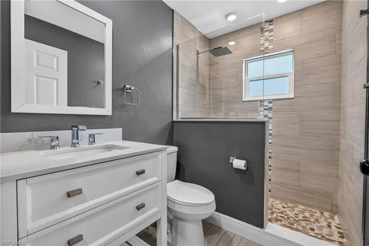 Bathroom featuring a white vanity with a quartz countertop, chrome fixtures, and a frameless glass shower enclosure