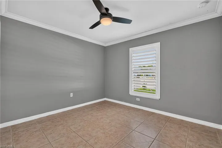 Room featuring neutral gray walls, crown molding, and tile flooring
