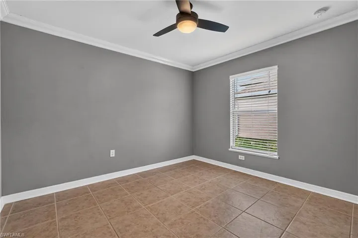 Room featuring tile flooring, crown molding, a window with horizontal blinds, a ceiling fan with integrated lighting, and neutral gray walls