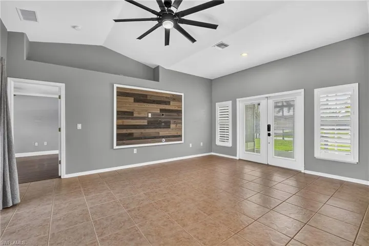 Spacious living area featuring tile flooring, vaulted ceilings, and a modern ceiling fan
