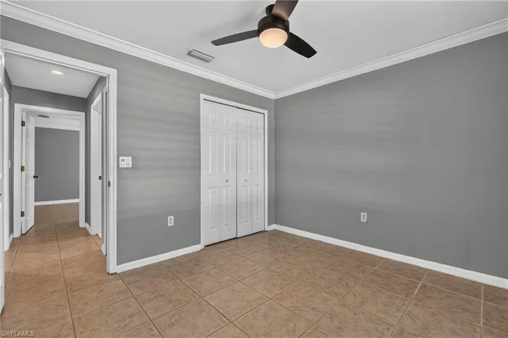 Interior room featuring ceramic tile flooring, a bi-fold closet, and a ceiling fan with integrated lighting