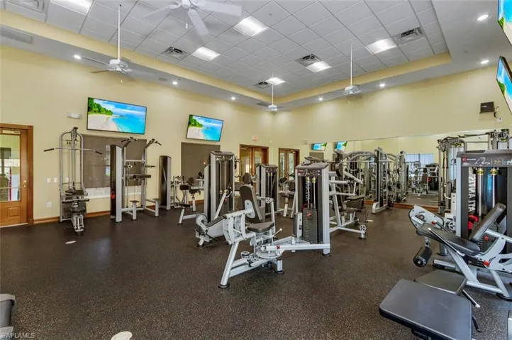Workout area with a paneled ceiling, a ceiling fan, and a high ceiling