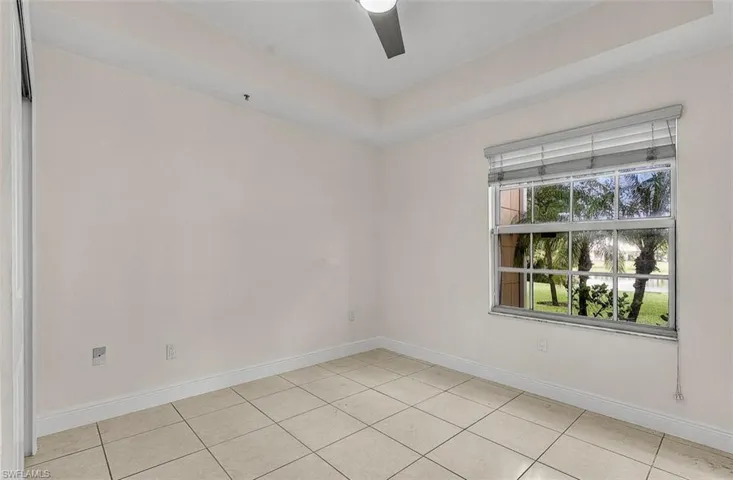 Unfurnished room with a raised ceiling, light tile patterned floors, and ceiling fan