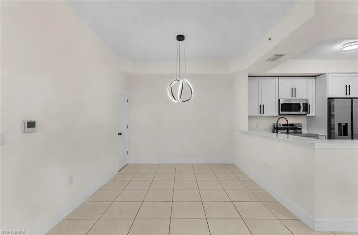 Kitchen with stainless steel appliances, white cabinets, light tile patterned floors, and a peninsula