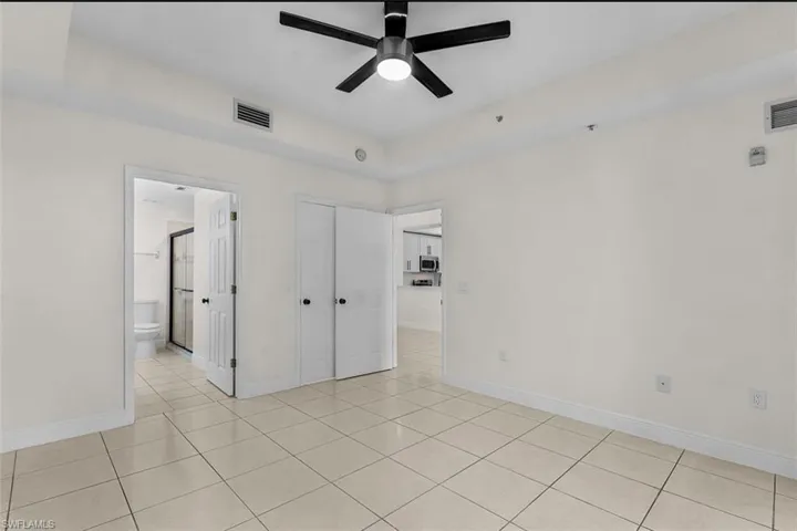 Unfurnished bedroom featuring a closet, light tile patterned floors, and a ceiling fan