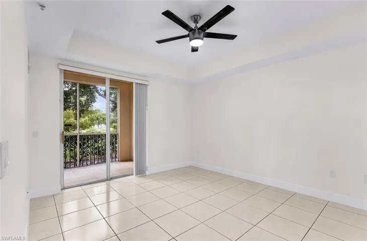 Unfurnished room featuring a raised ceiling, light tile patterned floors, and a ceiling fan