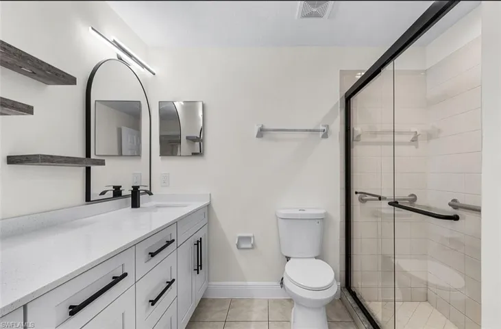 Full bath with vanity, light tile patterned floors, and a shower stall