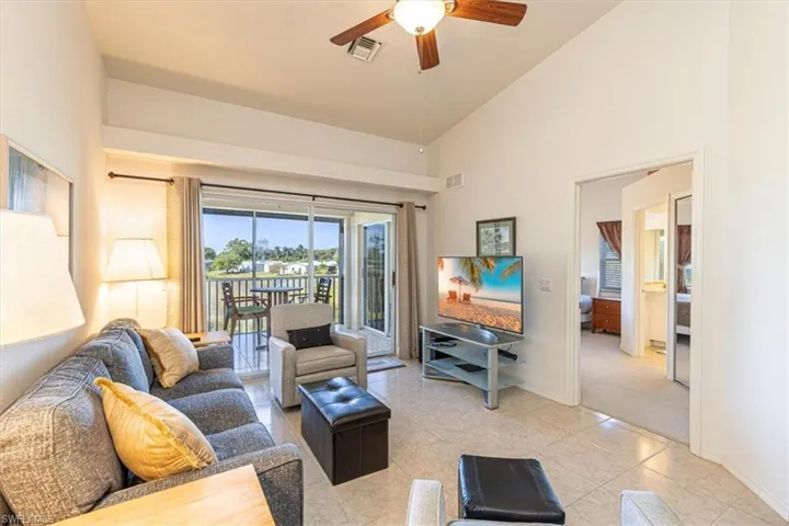 Tiled living area featuring ceiling fan and high vaulted ceiling