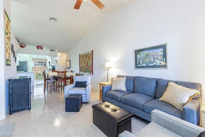 Tiled living room with ceiling fan and high vaulted ceiling