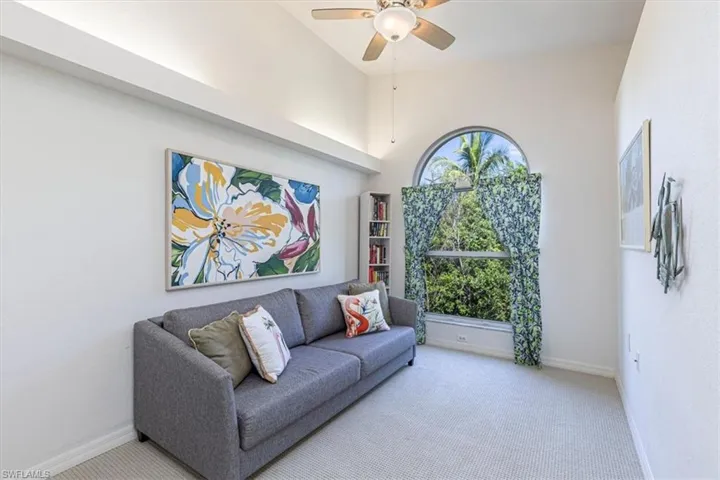 Living area with carpet floors, a towering ceiling, and a ceiling fan