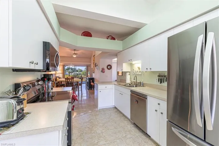 Kitchen with appliances with stainless steel finishes, white cabinets, light countertops, and a ceiling fan