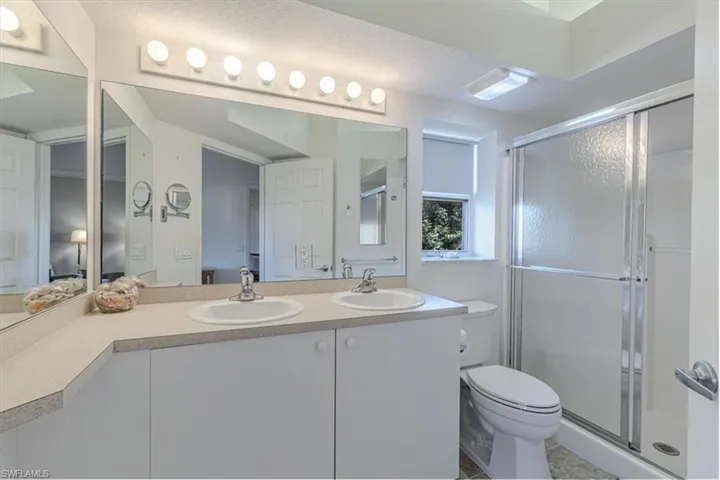 Full bath featuring double vanity and a stall shower