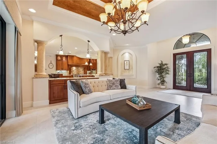 Living room featuring patterned floors, decorative columns, ornamental molding, and recessed lighting