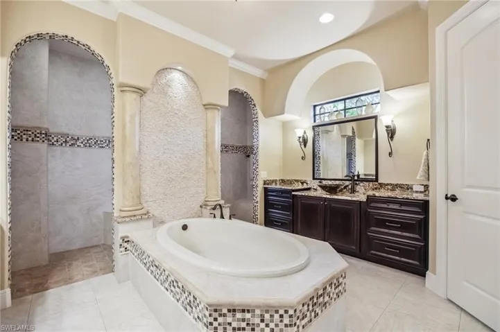 Full bathroom with dual vanities, a bath, ornamental molding, walk in shower, and light tile patterned floors