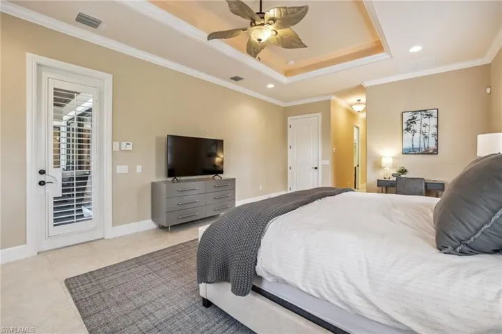 Bedroom featuring a tray ceiling, ornamental molding, private entrance to lanai, recessed lighting, and ceiling fan