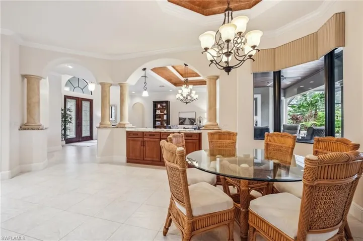 Dining space with a chandelier, ornamental molding, arched walkways, and a raised ceiling