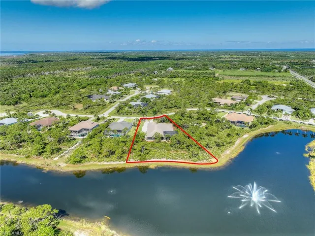 Aerial view of residential area featuring property boundaries highlighted and a nearby body of water