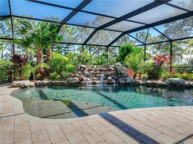 Outdoor pool featuring a lanai and waterfall