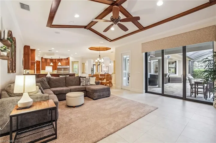 Living room featuring a chandelier, beam ceiling, light tile patterned flooring, ceiling fan, and recessed lighting