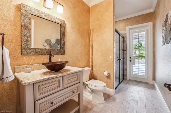 Full bath with ornamental molding, vanity, a shower stall, a textured wall, and light wood-type flooring
