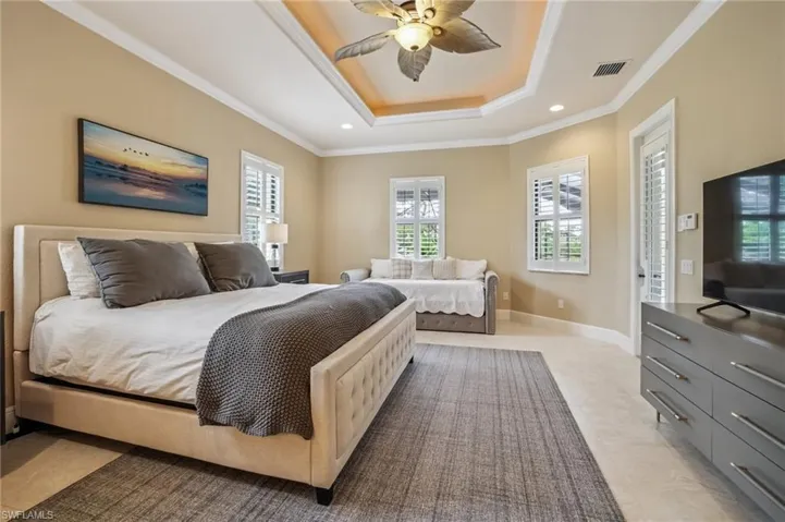 Bedroom featuring a tray ceiling, ornamental molding, a ceiling fan, and recessed lighting with private entrance to the lanai